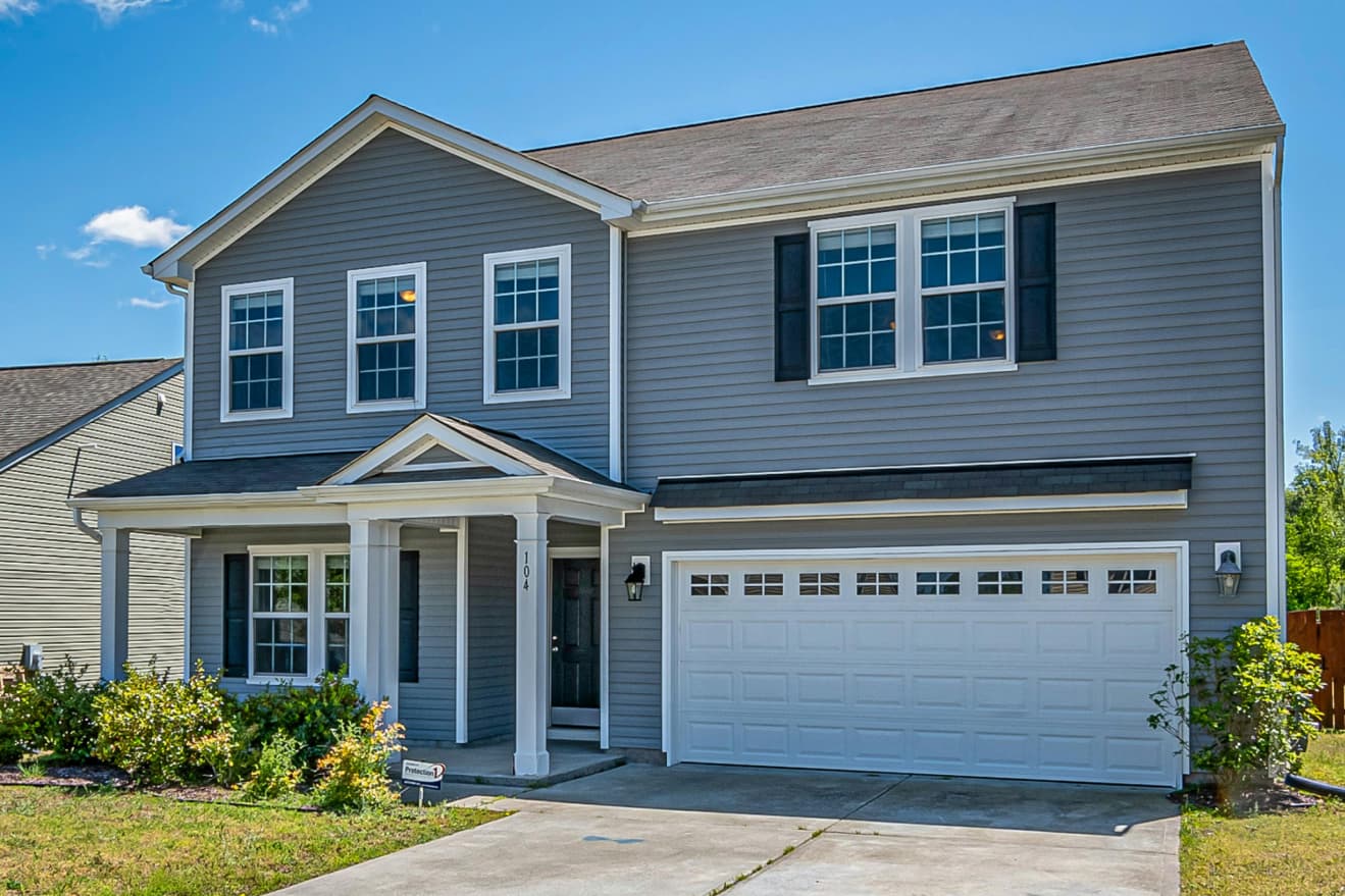 Completed two-story home with siding, porch columns and finished driveway